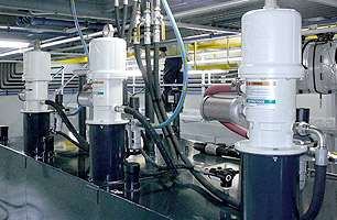 Oil and grease pumps connected to main lubrication supply tanks and high pressure lines in auto workshop